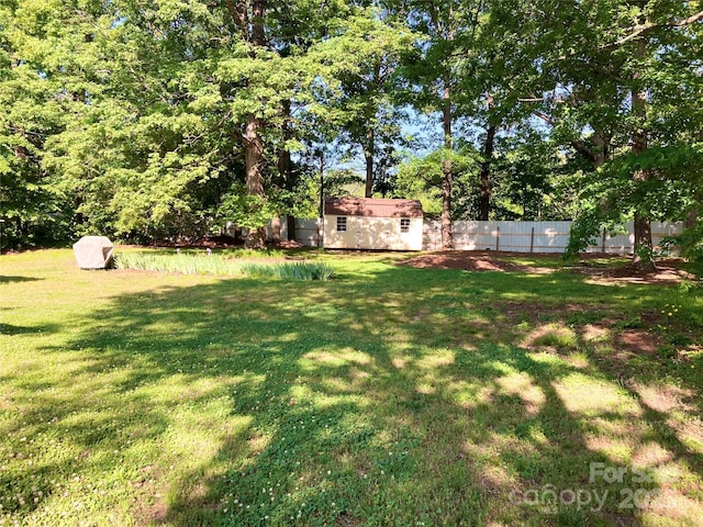 view of yard with fence, an outdoor structure, and a storage shed