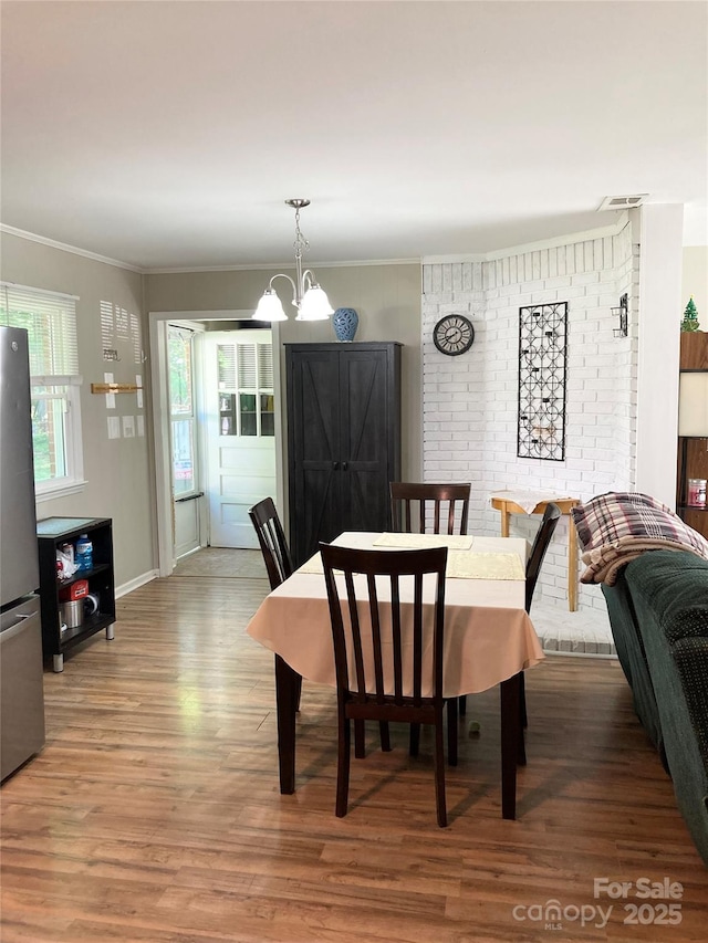 dining room with crown molding, visible vents, wood finished floors, baseboards, and a chandelier