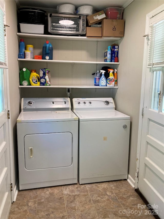 washroom with laundry area, stone finish flooring, a healthy amount of sunlight, and washer and clothes dryer