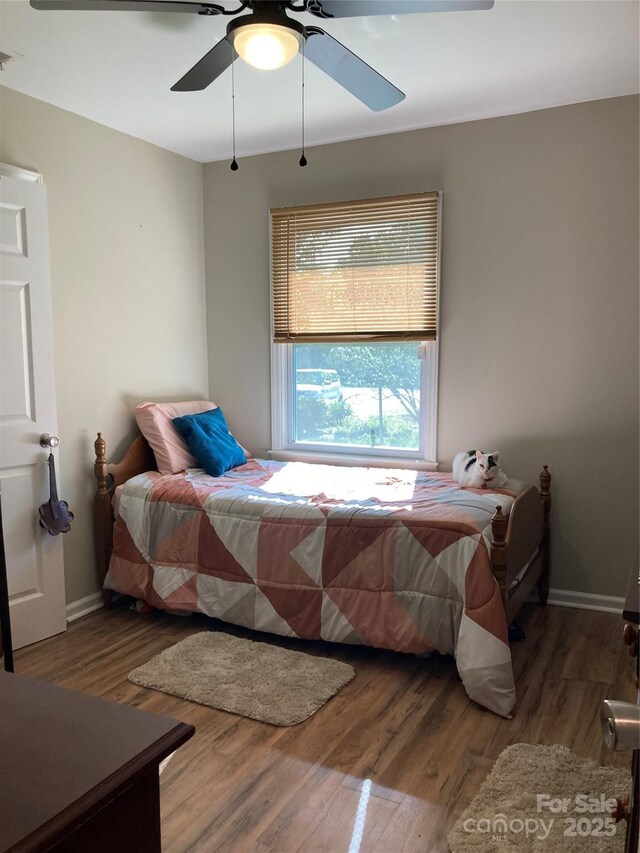 bedroom featuring a ceiling fan, baseboards, and wood finished floors