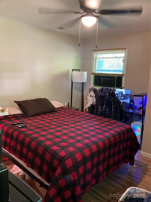 bedroom with visible vents, a ceiling fan, wood finished floors, and cooling unit