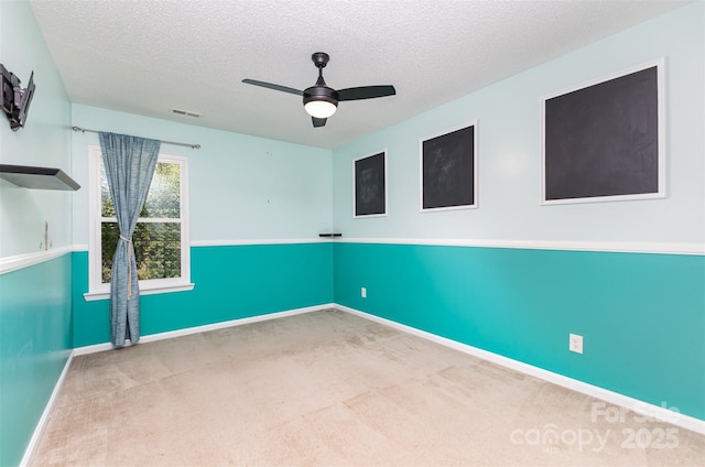 empty room featuring carpet floors, ceiling fan, a textured ceiling, and baseboards