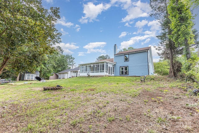 back of property featuring a sunroom, a storage shed, a chimney, a lawn, and an outdoor structure