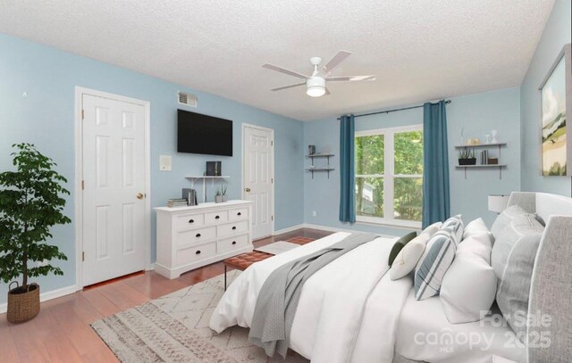 bedroom with a textured ceiling, wood finished floors, ceiling fan, and baseboards