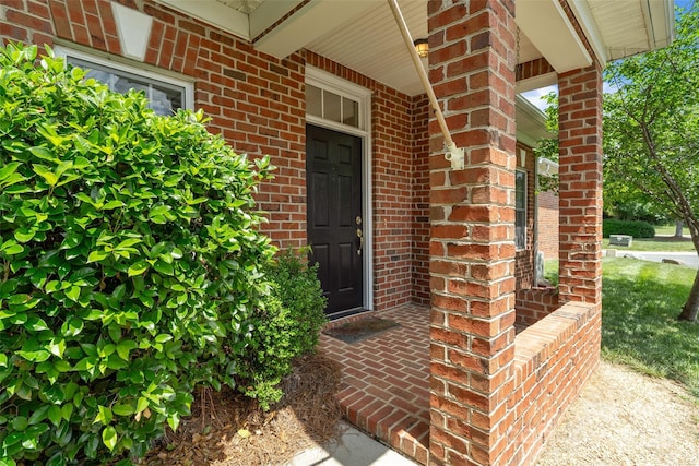 view of exterior entry with covered porch and brick siding
