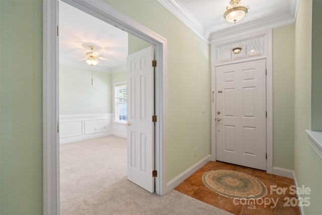 carpeted foyer with crown molding and ceiling fan