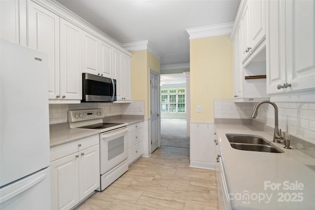 kitchen featuring white cabinets, ornamental molding, a sink, and white appliances