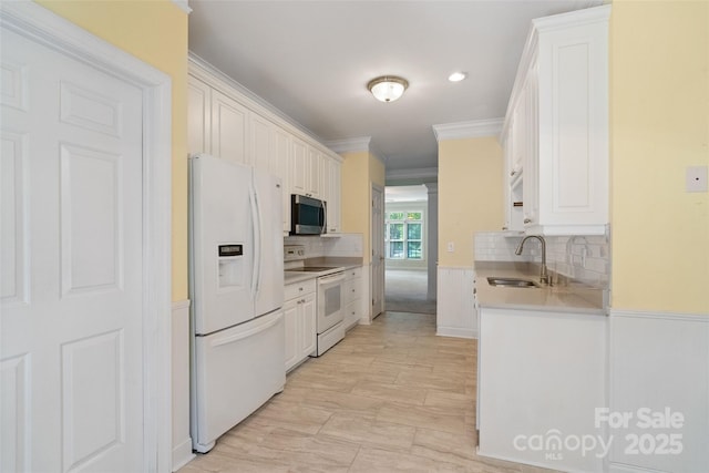 kitchen featuring ornamental molding, white appliances, a sink, backsplash, and light countertops