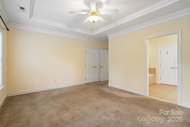 empty room featuring a ceiling fan, ornamental molding, visible vents, a raised ceiling, and carpet floors