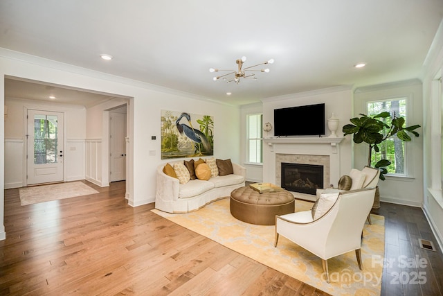 16432 Here At Last Ln, Charlotte, NC 28278 - living room featuring a notable chandelier, a glass covered fireplace, wood finished floors, visible vents, and ornamental molding