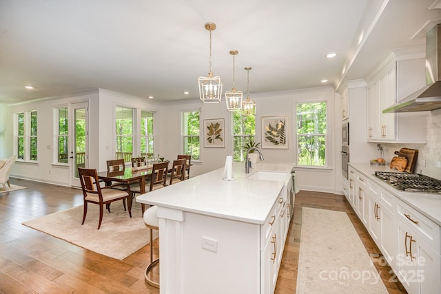 16432 Here At Last Ln, Charlotte, NC 28278 - kitchen with a kitchen island with sink, a sink, light countertops, stainless steel appliances, and wall chimney exhaust hood