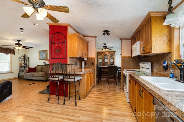 kitchen with brown cabinets, white appliances, ceiling fan, and a sink