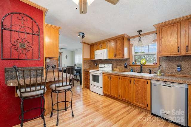 kitchen featuring light wood-type flooring, white appliances, ceiling fan, and a sink