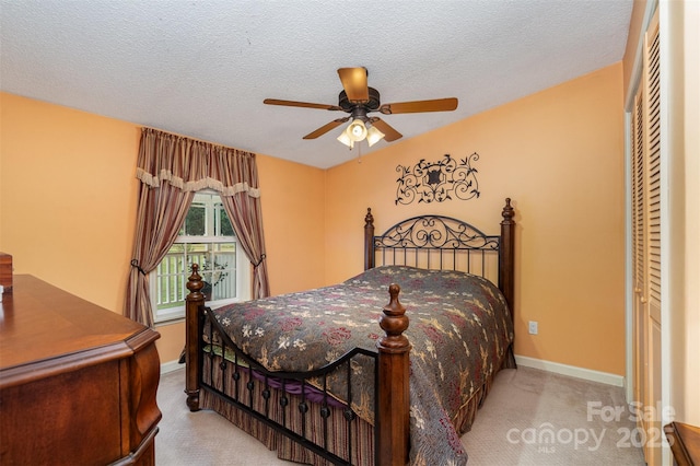 carpeted bedroom with ceiling fan, a textured ceiling, baseboards, and a closet
