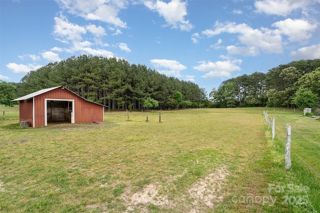 view of yard with a pole building, a wooded view, fence, and a garage