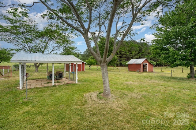 view of yard featuring exterior structure, an outbuilding, fence, and a carport