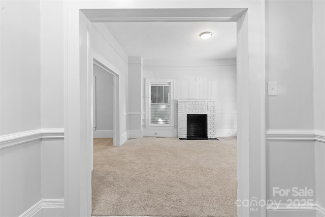 unfurnished living room with carpet and a brick fireplace