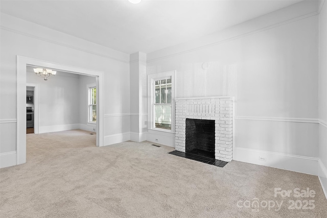 unfurnished living room with a fireplace, carpet floors, a notable chandelier, and visible vents