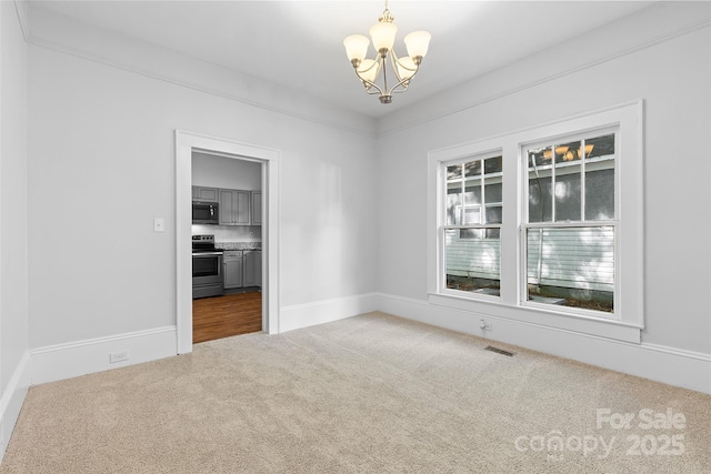 carpeted spare room featuring a chandelier, baseboards, and visible vents