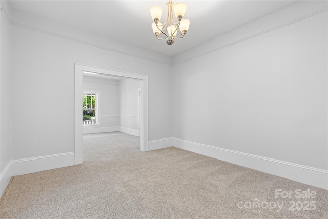 empty room featuring carpet flooring, a chandelier, and baseboards