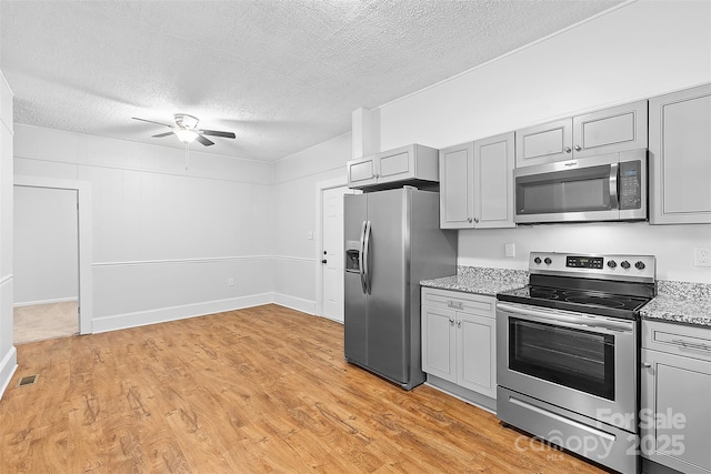 kitchen with a ceiling fan, stainless steel appliances, a textured ceiling, visible vents, and gray cabinetry