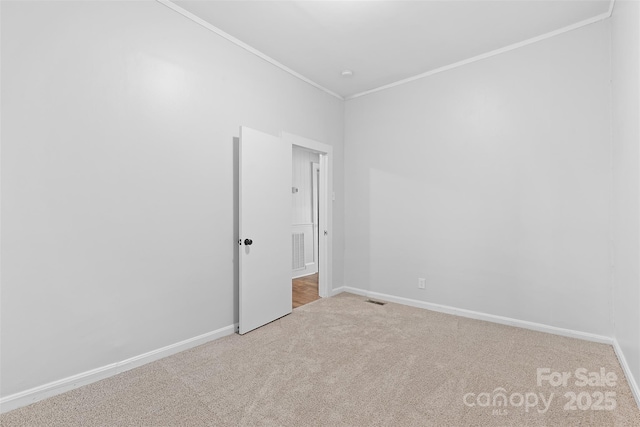 unfurnished room with baseboards, carpet flooring, visible vents, and crown molding