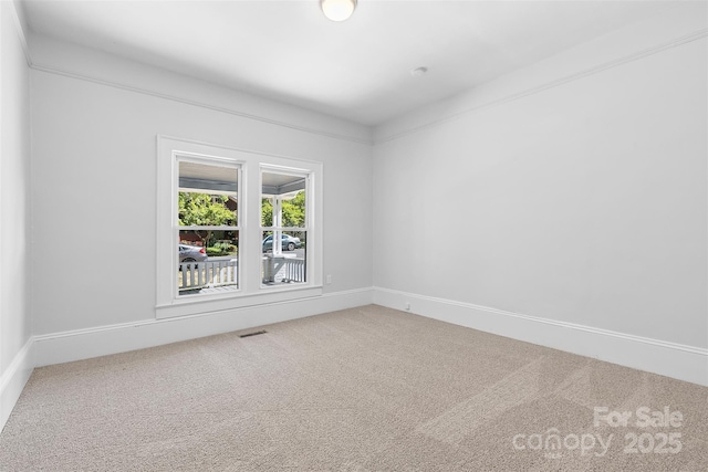 unfurnished room with carpet flooring, visible vents, and baseboards