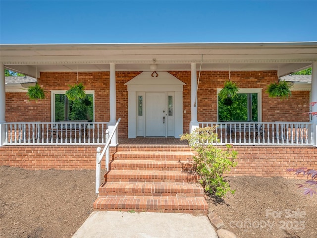entrance to property featuring covered porch and brick siding