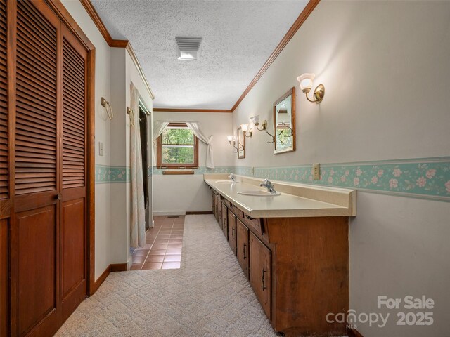 bathroom with vanity, ornamental molding, a textured ceiling, and a wainscoted wall