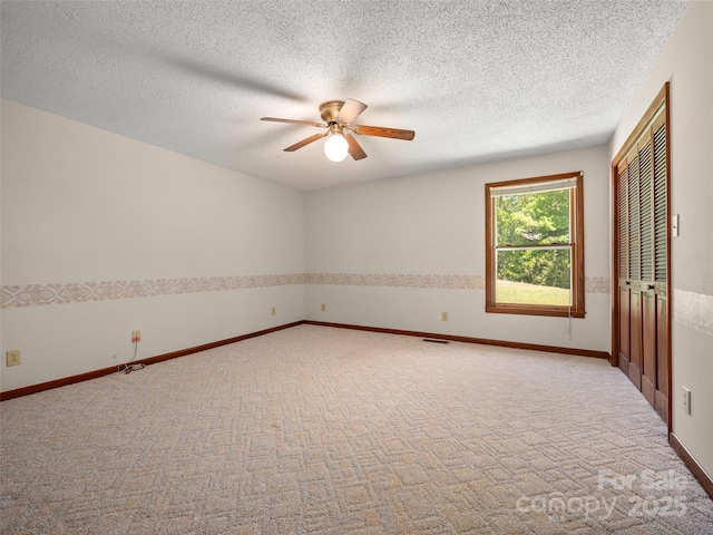 unfurnished room with ceiling fan, a textured ceiling, visible vents, light colored carpet, and baseboards