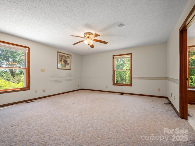 empty room featuring a ceiling fan, visible vents, and light carpet