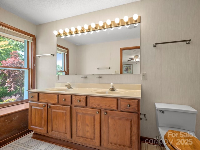 bathroom featuring a sink, a ceiling fan, toilet, and double vanity