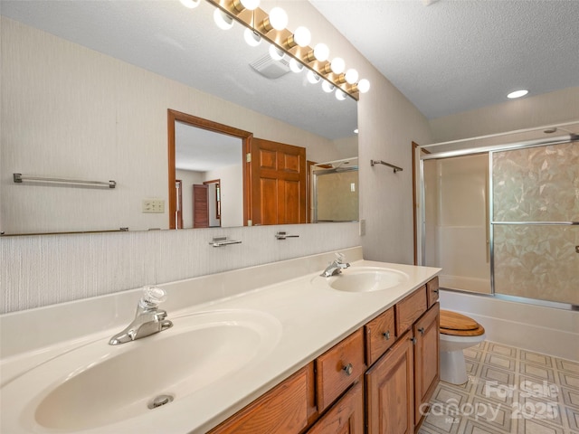 full bathroom featuring double vanity, a sink, enclosed tub / shower combo, and toilet