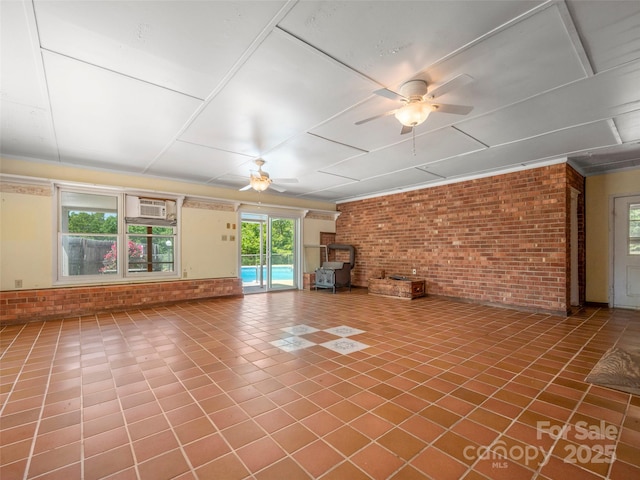 unfurnished living room featuring tile patterned flooring, a wood stove, brick wall, ceiling fan, and a wall mounted AC