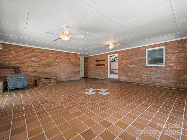 basement with ceiling fan, a wood stove, and brick wall
