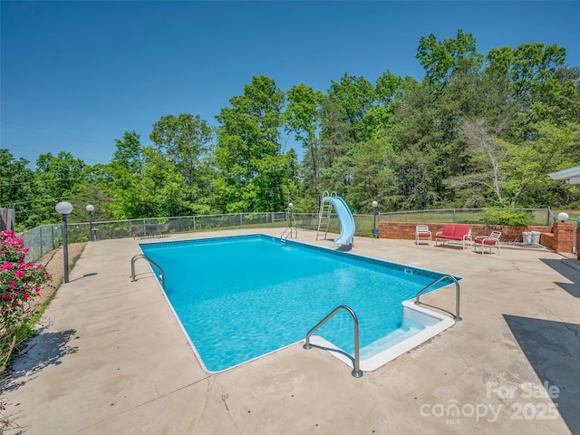 view of swimming pool with fence, a water slide, a patio area, and a fenced in pool