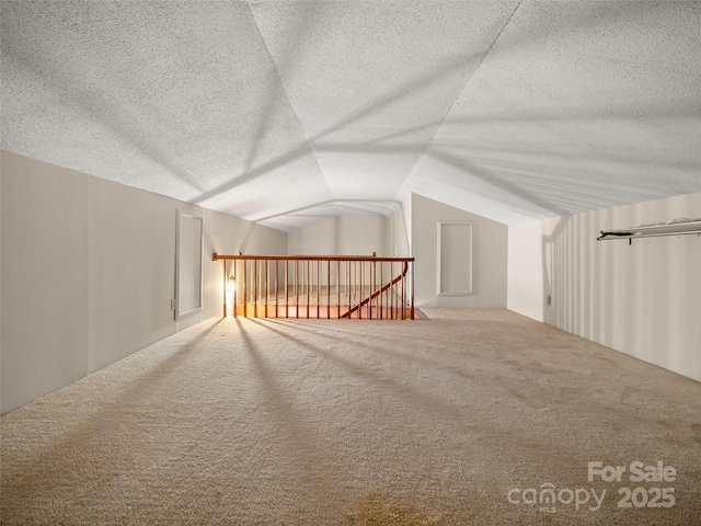 bonus room with carpet floors, a textured ceiling, and lofted ceiling