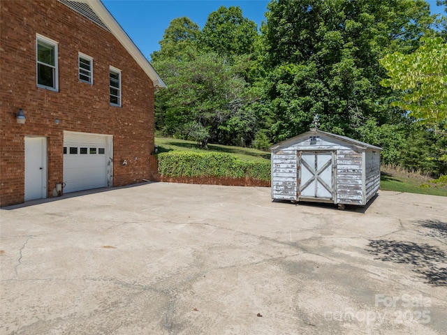 view of property exterior with a storage unit, brick siding, concrete driveway, an attached garage, and an outbuilding