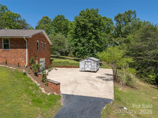 view of patio / terrace featuring an attached garage, an outdoor structure, driveway, and a storage unit