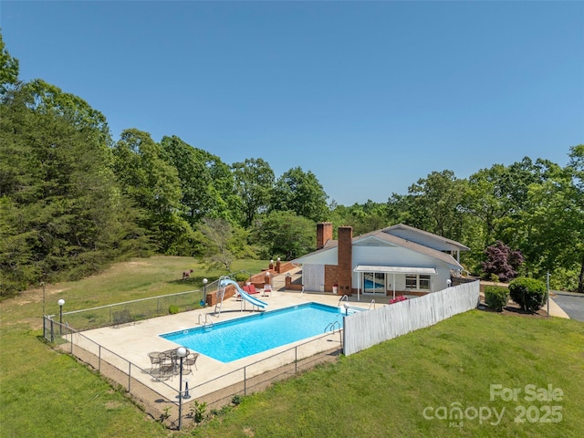 view of pool with a water slide, a yard, and fence