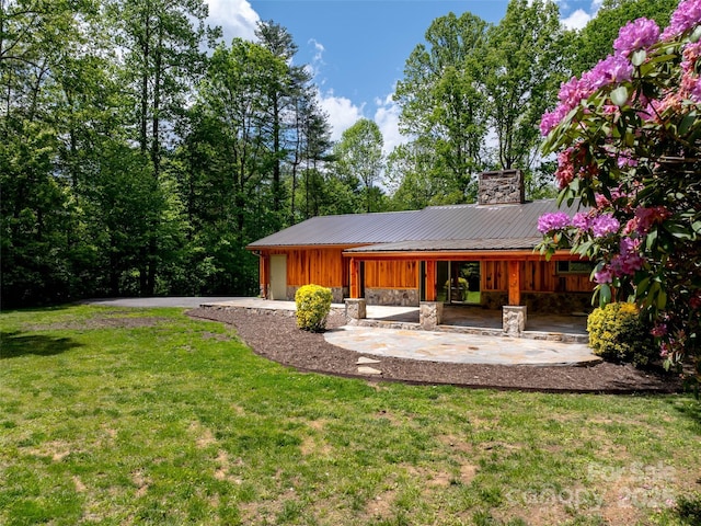 100 Ashton Ln, Brevard, NC 28712 - rear view of house featuring a chimney, an attached garage, a lawn, asphalt driveway, and board and batten siding