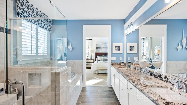 ensuite bathroom featuring a sink, a stall shower, double vanity, and connected bathroom