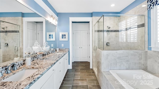 full bath with double vanity, a sink, a bath, and a stall shower