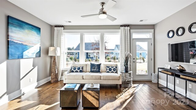 living area featuring baseboards, ceiling fan, wood finished floors, and visible vents
