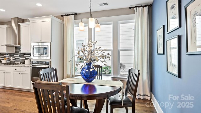 dining area with recessed lighting, visible vents, a wealth of natural light, and wood finished floors