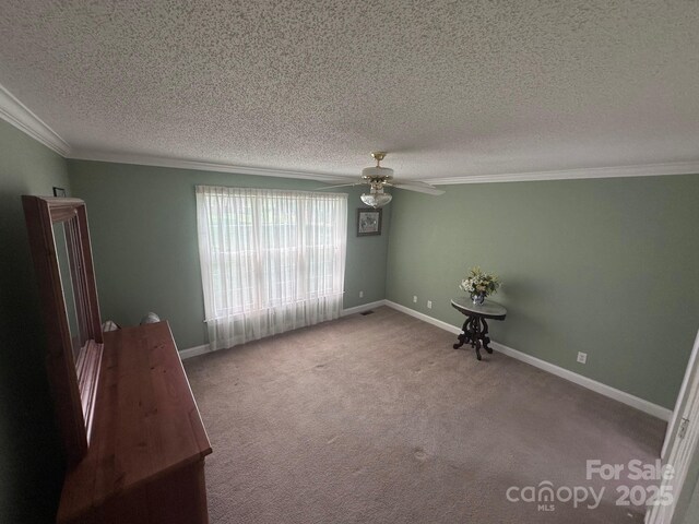 carpeted spare room featuring crown molding, a ceiling fan, a textured ceiling, and baseboards