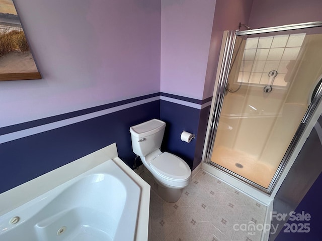bathroom featuring toilet, baseboards, a shower stall, and a jetted tub