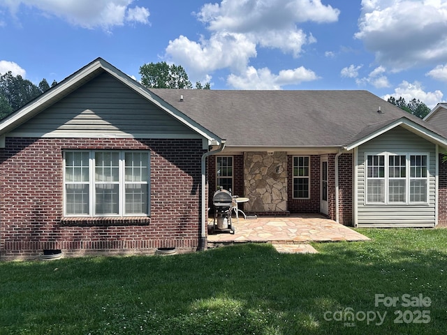back of house featuring a lawn, a patio area, and brick siding
