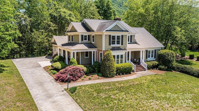 view of front facade with a chimney, concrete driveway, a porch, and a front yard