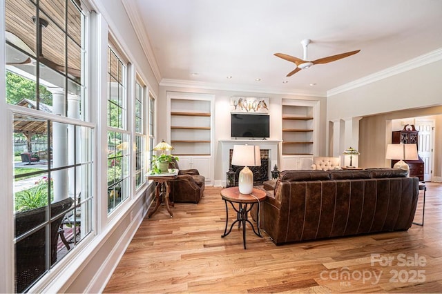 living area with ornamental molding, built in features, and a healthy amount of sunlight